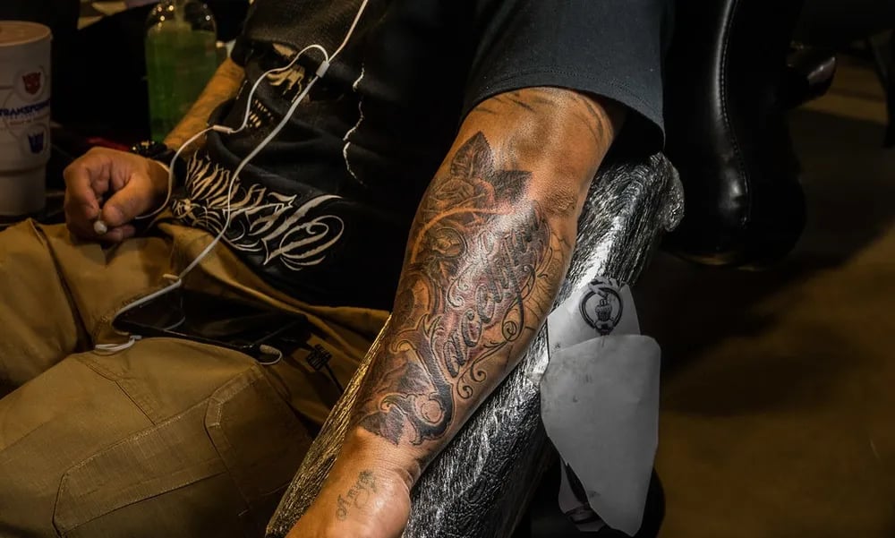 Black and grey forearm sleeve being tattooed at a convention