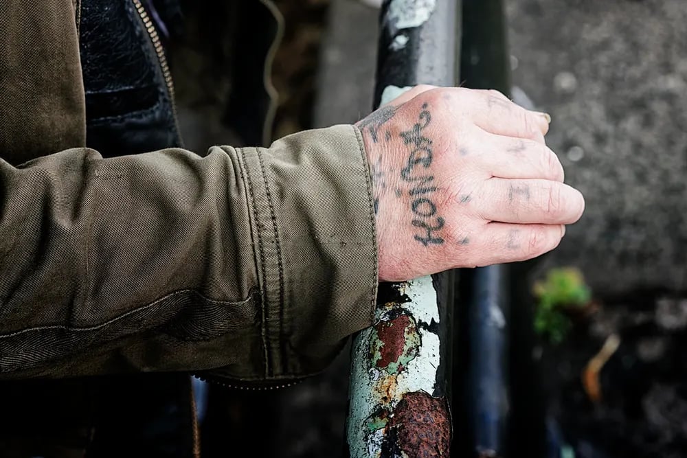 Hand with script lettering tattooed across the knuckles