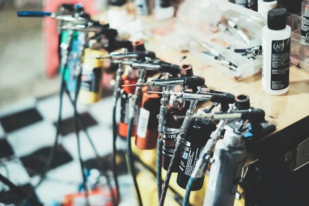 Row of tattoo machines and ink bottles on a workbench
