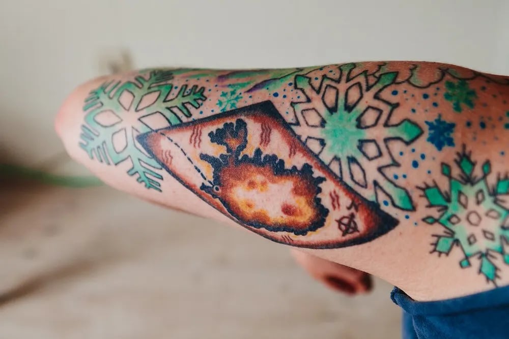 Colour elbow tattoo of snowflakes around an island