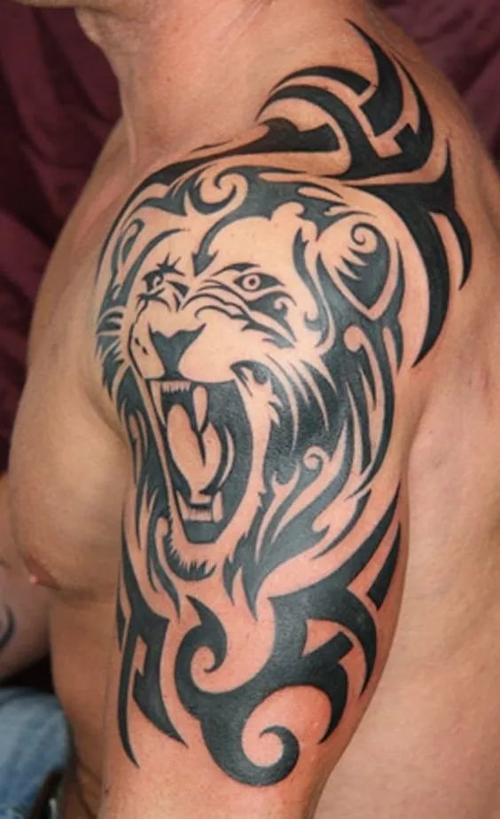 Bold black tribal lion tattoo wrapping over a man's shoulder onto his chest