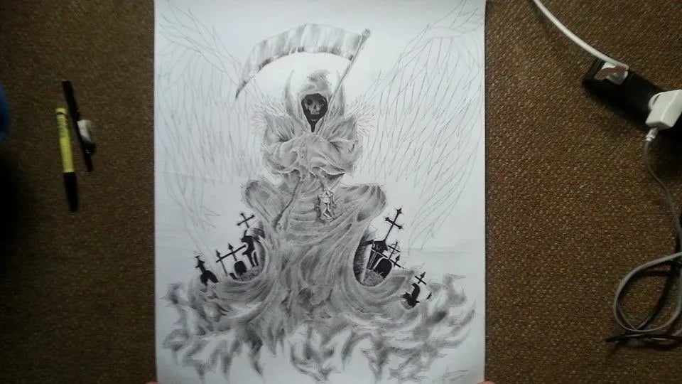 Pencil drawing of a reaper over gravestones, shaded on a desk beside a pen