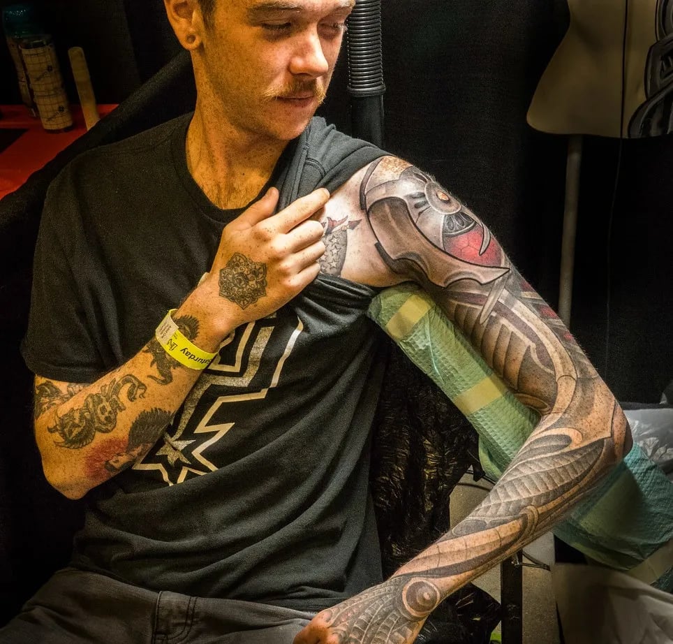 Man showing a black and grey biomechanical full sleeve from shoulder to hand